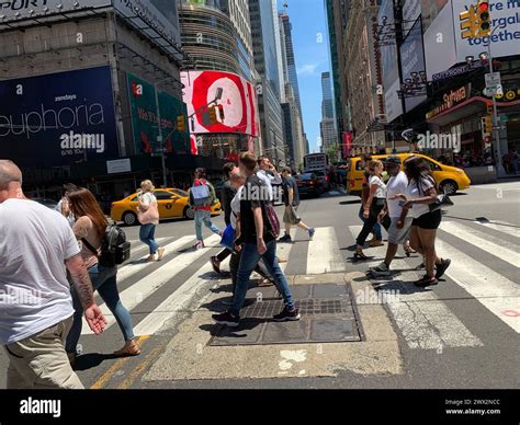 Pedestrians are surrounded by video billboards as they cross the street ...