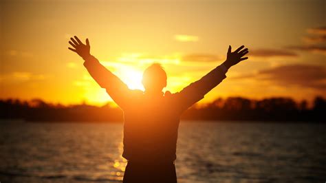 1-26-CH Man arms raised in praise to God at sunset over water