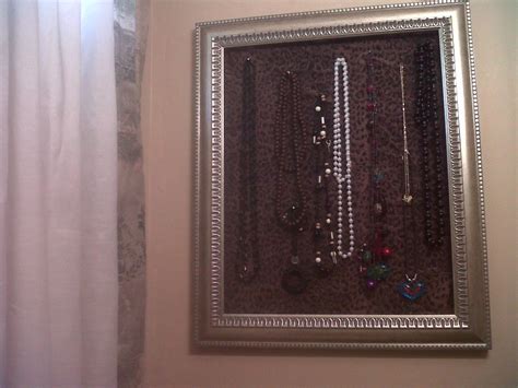 a picture frame with fabric behind it and tome pins to hold neckless ...