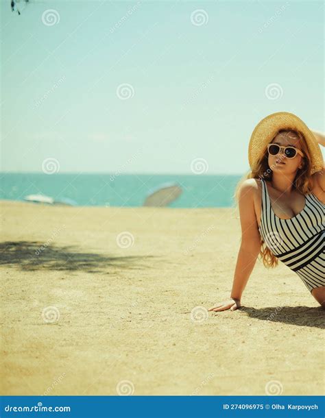 A Beautiful Blonde is Sunbathing on the Beach in a One-piece Swimsuit ...