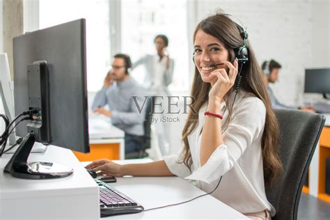 年轻友好的接线员，女代理人与耳机在呼叫中心工作。照片摄影图片_ID:309794878-Veer图库