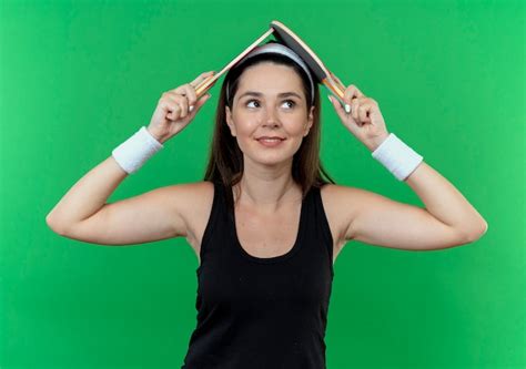 Young fitness woman in headband holding two rackets for table tennis ...