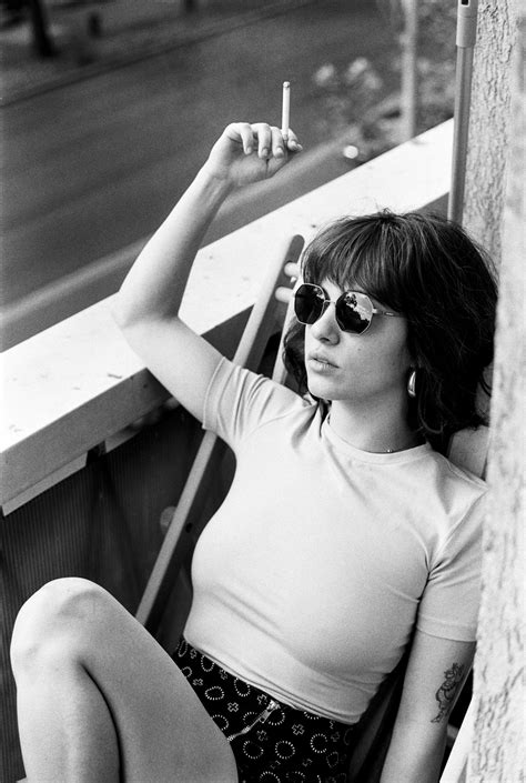 A woman sitting on a ledge smoking a cigarette photo - Free Bucharest ...