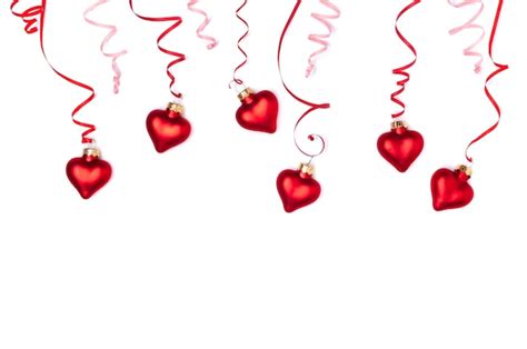 Red ribbon in the form of serpentine and red glass hearts on a white ...