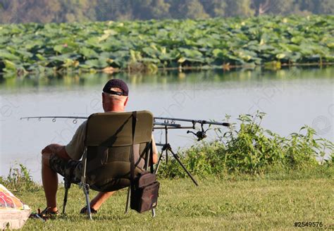 Sporty fisherman sitting fishing on the lake shore - stock photo ...