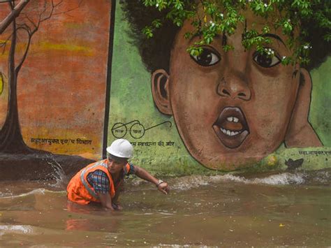 Cleaning an open manhole - Rain shuts down Mumbai, flights and trains ...