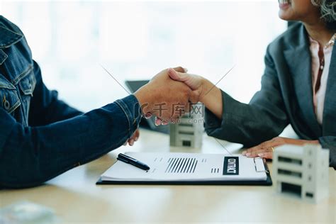 银行房贷专员与客户握手祝贺客户签订购房投资贷款协议高清摄影大图-千库网