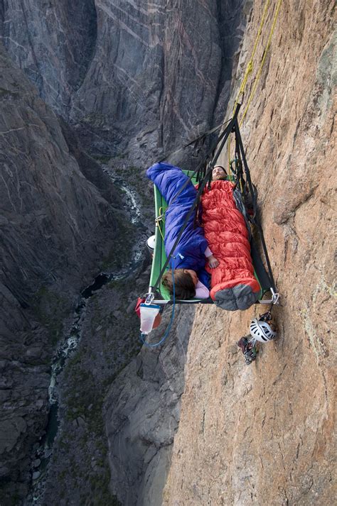 A man and woman sleep on portaledge while rock climbing a vertical face ...