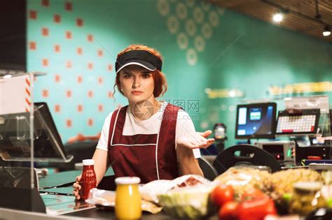 穿着制服的年轻不高兴女出纳在现代超市工作时高清图片下载-正版图片505473079-摄图网