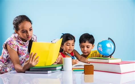Cute little indian or asian kids studying on study table with pile of ...