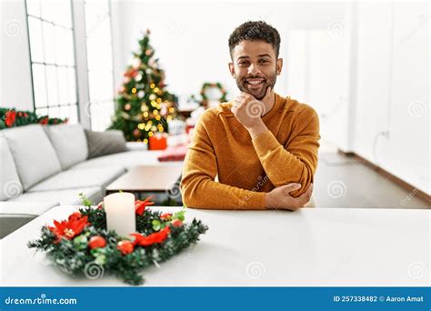 Arab Young Man Sitting on the Table by Christmas Tree Looking Confident ...