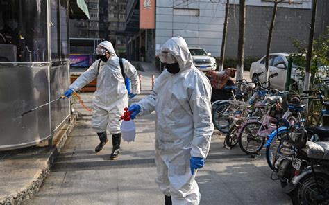 2020年1月30日，穿着防护服的工作人员为湖北省武汉市的一个地区进行消毒防疫工作。（图片来源：HECTOR RETAMALAFP via ...