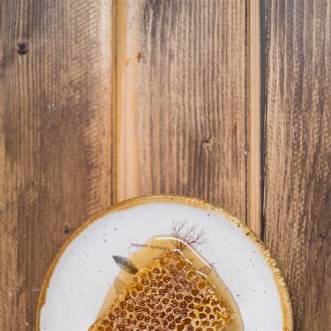 An overhead view of honeycomb on plate over wooden backdrop | Free Photo