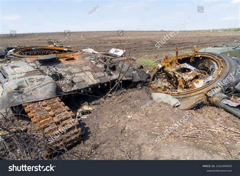 A man walks past a burnt armoured personnel carrier near buildings destroyed in the course of Ukrain