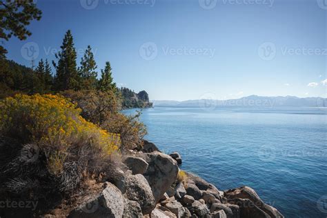 Tranquil lakeside landscape with rocky outcrop, vibrant vegetation ...