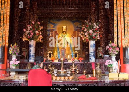 Tao monk lights candles at the shrine of the god called Xian Zu Dian at ...