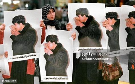 Black-and-white photo of Saddam Hussein, in a suit, with a group of women students