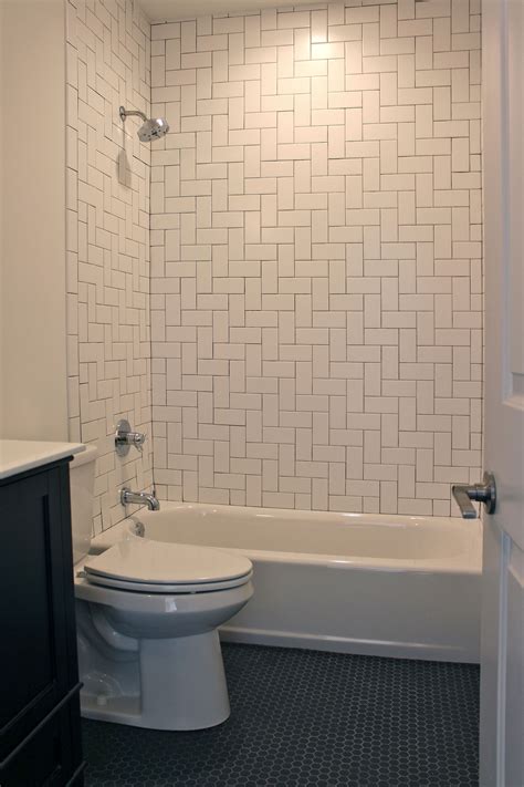 Bathroom with herringbone pattern white subway tile surround and black ...