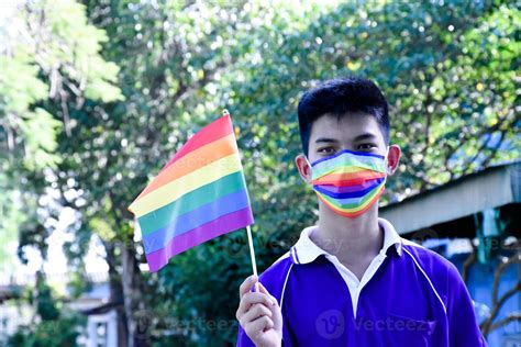 Portrait of young asian boy wears rainbow mask and holding rainbow flag ...