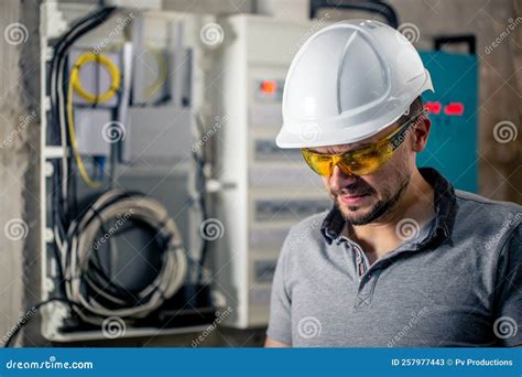 Male Electrician with Safety Glasses and a Helmet Near the Switchboard ...