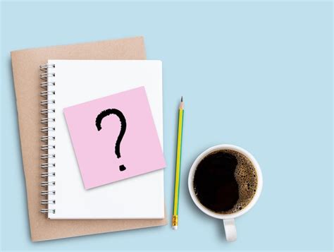 Question mark on pink sticky note with pencil and coffee on blue table ...
