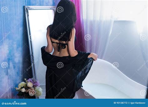 Beautiful Woman Taking Off Clothes in Bedroom, Sitting on Bed Stock Image