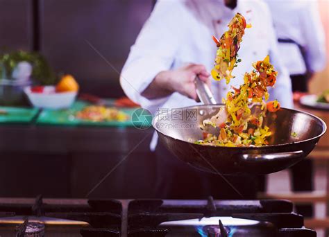 轻的男厨师商业厨房的炒菜厨师炒菜高清图片下载-正版图片300114663-摄图网