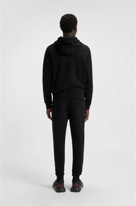 HUGO - Cotton-terry tracksuit bottoms with red logo label - Black