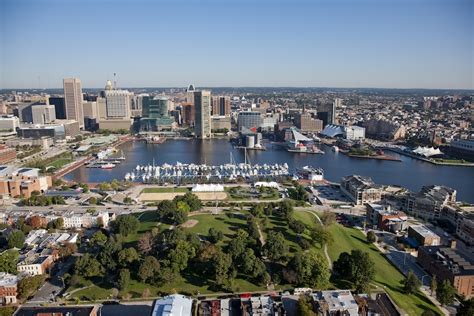 Aerial view of Baltimore's Inner Harbor with city skyline, waterfront, and green park areas, representing managed IT services in Maryland.