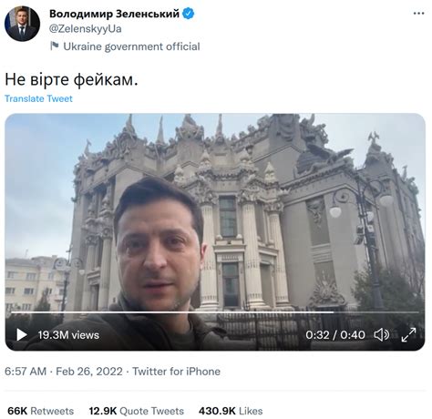 Zelensky wearing a green shirt speaks in a dimly-lit room. An out-of-focus Christmas tree is in the