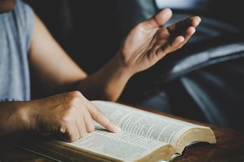 Spirituality and religion, hands folded in prayer on a holy bible in ...