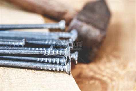 棕色的木板背景上带钉子的旧锤建筑工程具特写板子背景上带钉的旧锤桌生锈的高清图片下载-正版图片307703683-摄图网