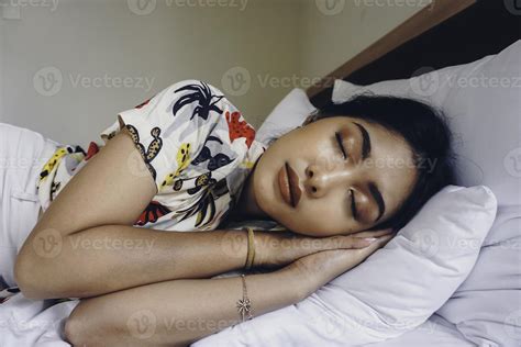 Young attractive woman sleeping in the bedroom, she is lying on the side and relaxing with eyes ...