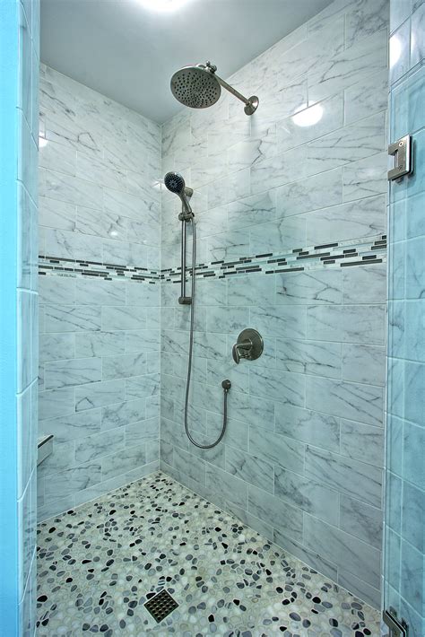 Custom tiled shower with porcelain tiles that look like marble, pebbles ...