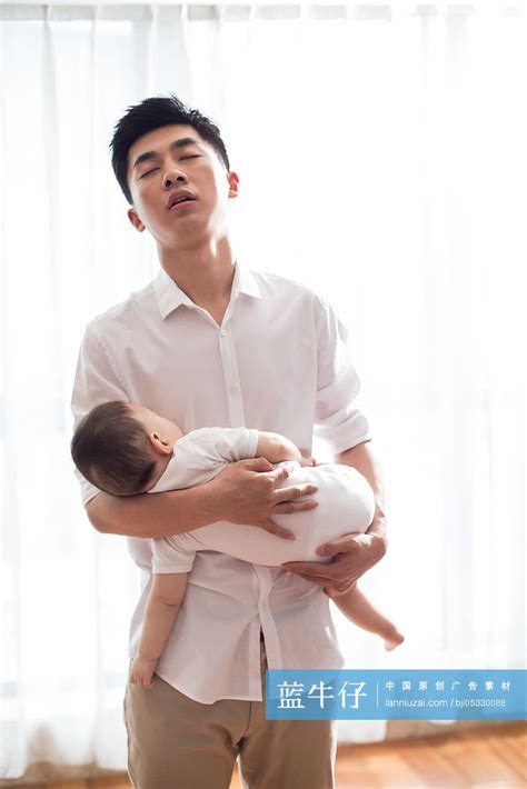 疲倦的年轻爸爸抱着熟睡的宝宝-蓝牛仔影像-中国原创广告影像素材