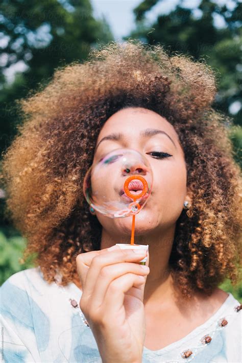 "Girl With Big Afro Blowing Bubbles In The Park" by Stocksy Contributor "Ivo De Bruijn" - Stocksy