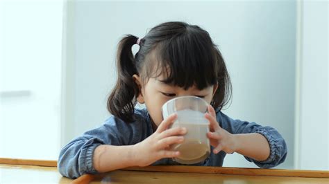 little Asian girl drinking Chocolate milk. Cute Girl having breakfast ...