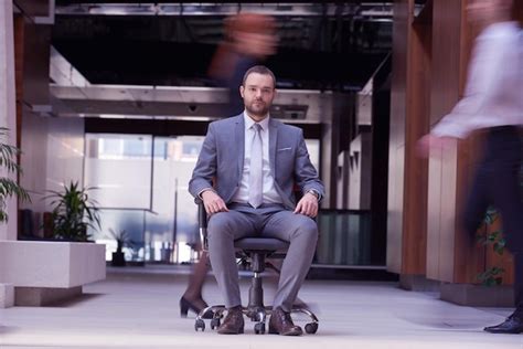 Business man sitting in office chair, people group passing by: concept ...