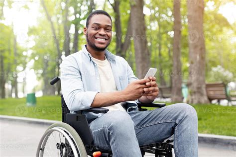 Happy disabled black man in wheelchair using smartphone, checking ...