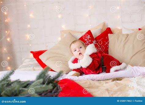 A Little Girl Under One Year Old Dressed As Santa Claus on a Large Bed ...