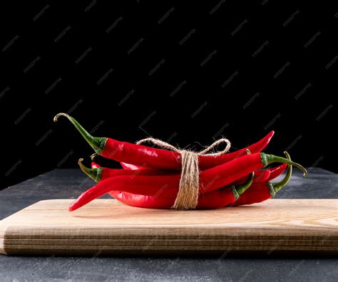 Side view red chili pepper on wooden cutting board on black | Free Photo