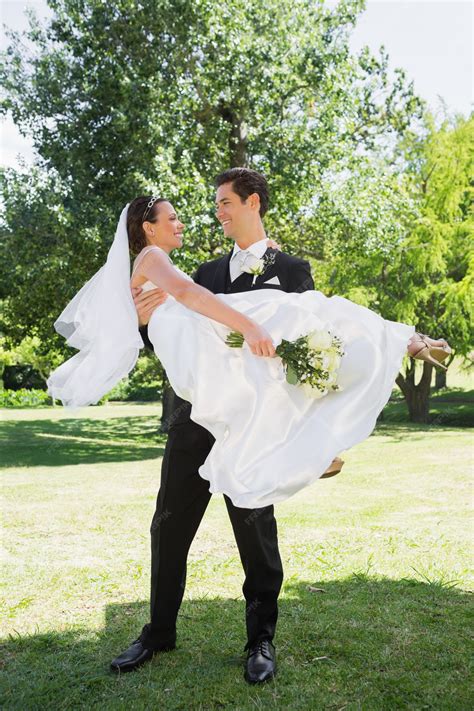 Premium Photo | Happy groom carrying bride in arms at garden