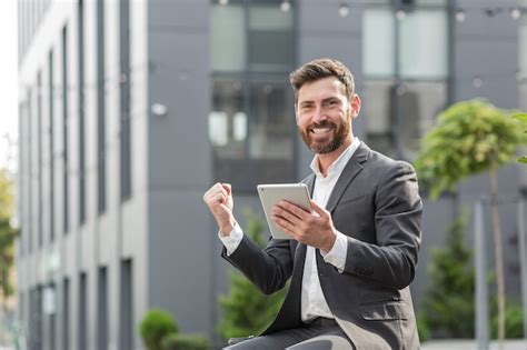 Successful male businessman got good win news reads them from a tablet ...