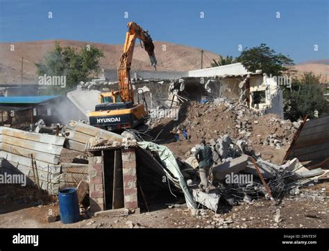 People watch an Israeli army bulldozer demolishing homes in the Palestinian urban refugee camp of Nu
