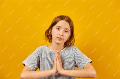 Premium Photo | Pleading teen girl on yellow studio background wish and ...