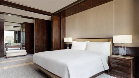 JW Marriott bed in hotel room with logo on an accent pillow