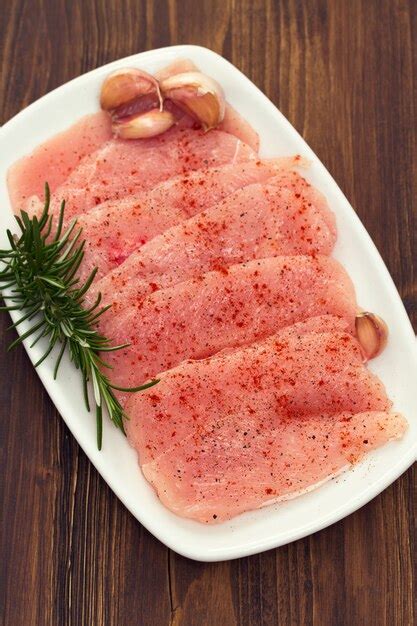 Raw turkey with pepper and rosemary on white dish | Premium Photo