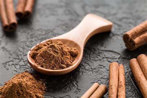 Ground cinnamon spice powder in wooden spoon, | Premium Photo