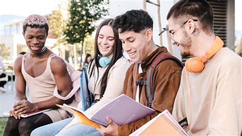Multiracial group of friends studying together sitting in a park ...