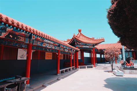 Photo of an elaborate Chinese temple with hedges in front.